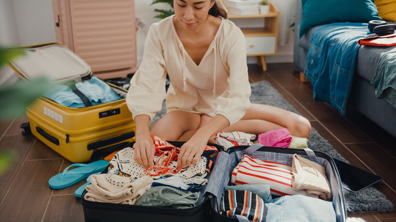 Woman packing swimsuit in suitcase