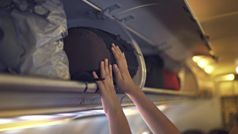 Passenger storing luggage in an overhead bin