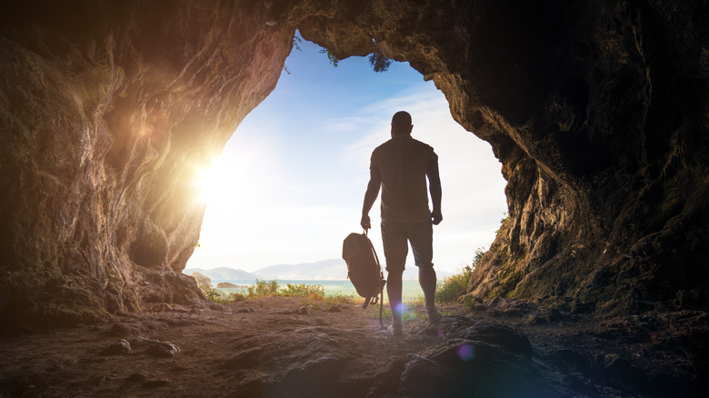 Spelunker standing at cave entrance