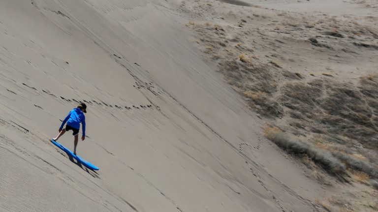 Boy sandboarding on the dunes