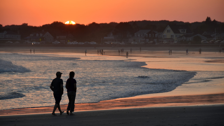 couple walking on beach at sunset