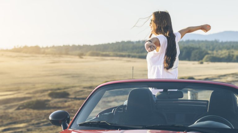 Woman outstretching arms in car