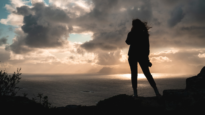 woman stands alone on mountaintop