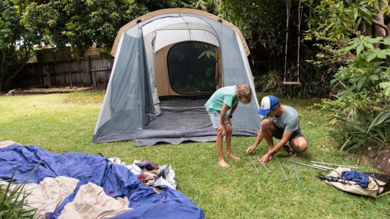 two boys setting up tent in back yard