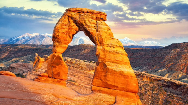 Delicate Arch at sunset with mountains in the background