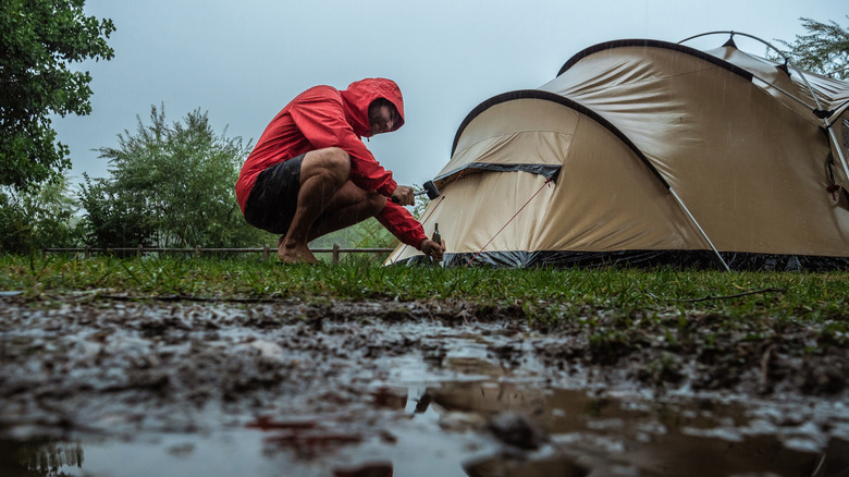 Man fixing tent in the rain