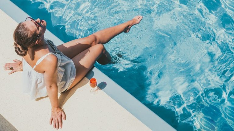 woman sitting poolside on deck of cruise ship with drink