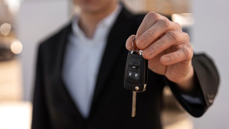 man holding out car keys